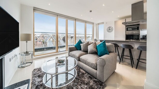 Un salon moderne avec un canapé, une table basse et une grande fenêtre donnant sur la ville.