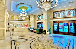 Um hall imponente com recepção, lustres e um desenho de piso grande e ornamentado.