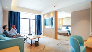 Een hotelkamer met een bank, bureau, bed en televisie.