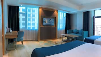 A hotel room with a bed, a sofa, a desk with a chair, a TV, and a window with curtains.