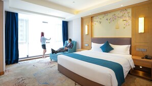 Een hotelkamer met een groot bed, een zithoek en uitzicht.