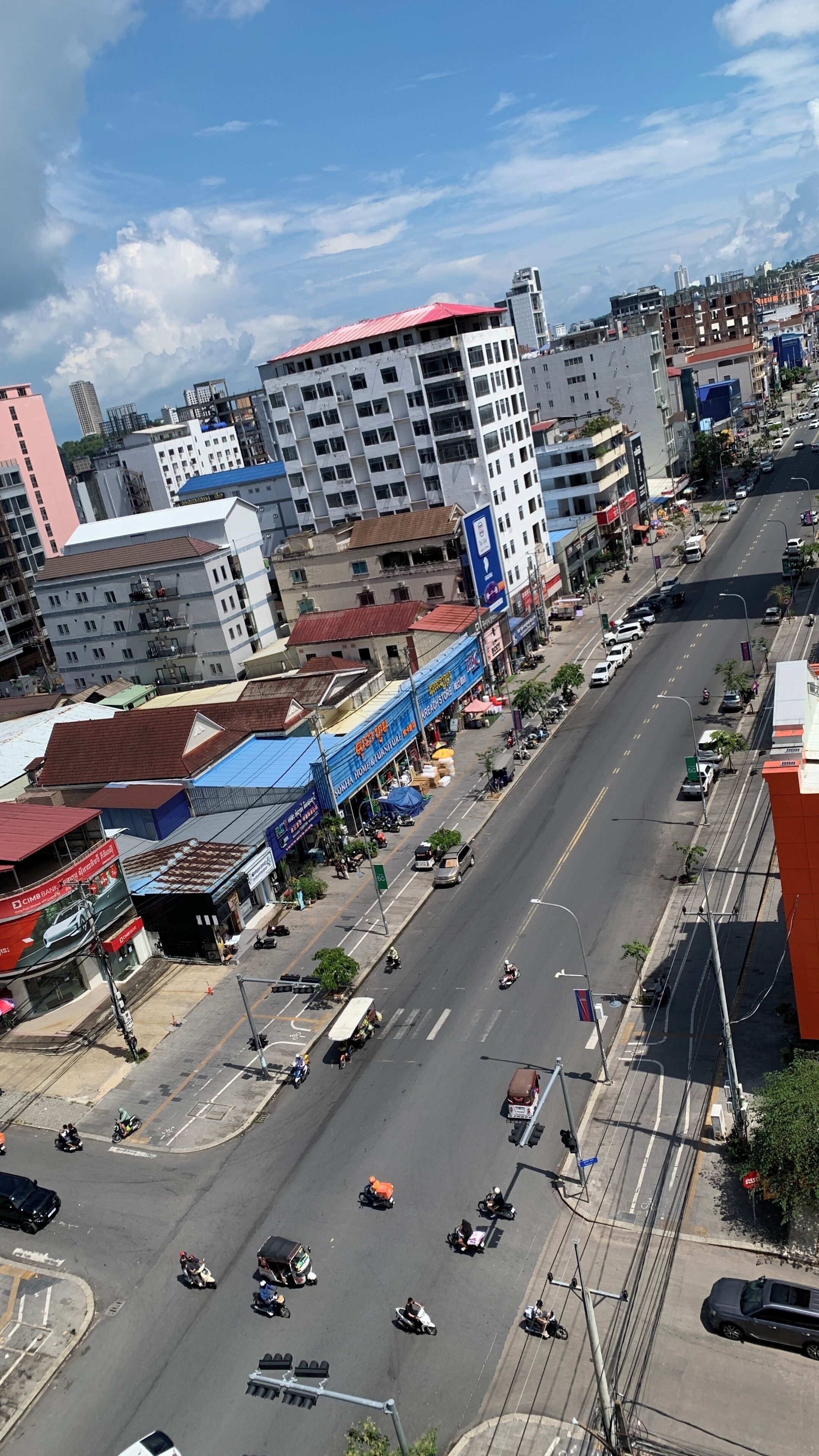Una calle urbana con edificios, vehículos y cielo despejado.
