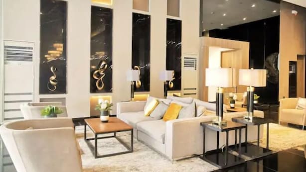 A modern living room with a sofa, armchairs, a coffee table, and a glass coffee table.