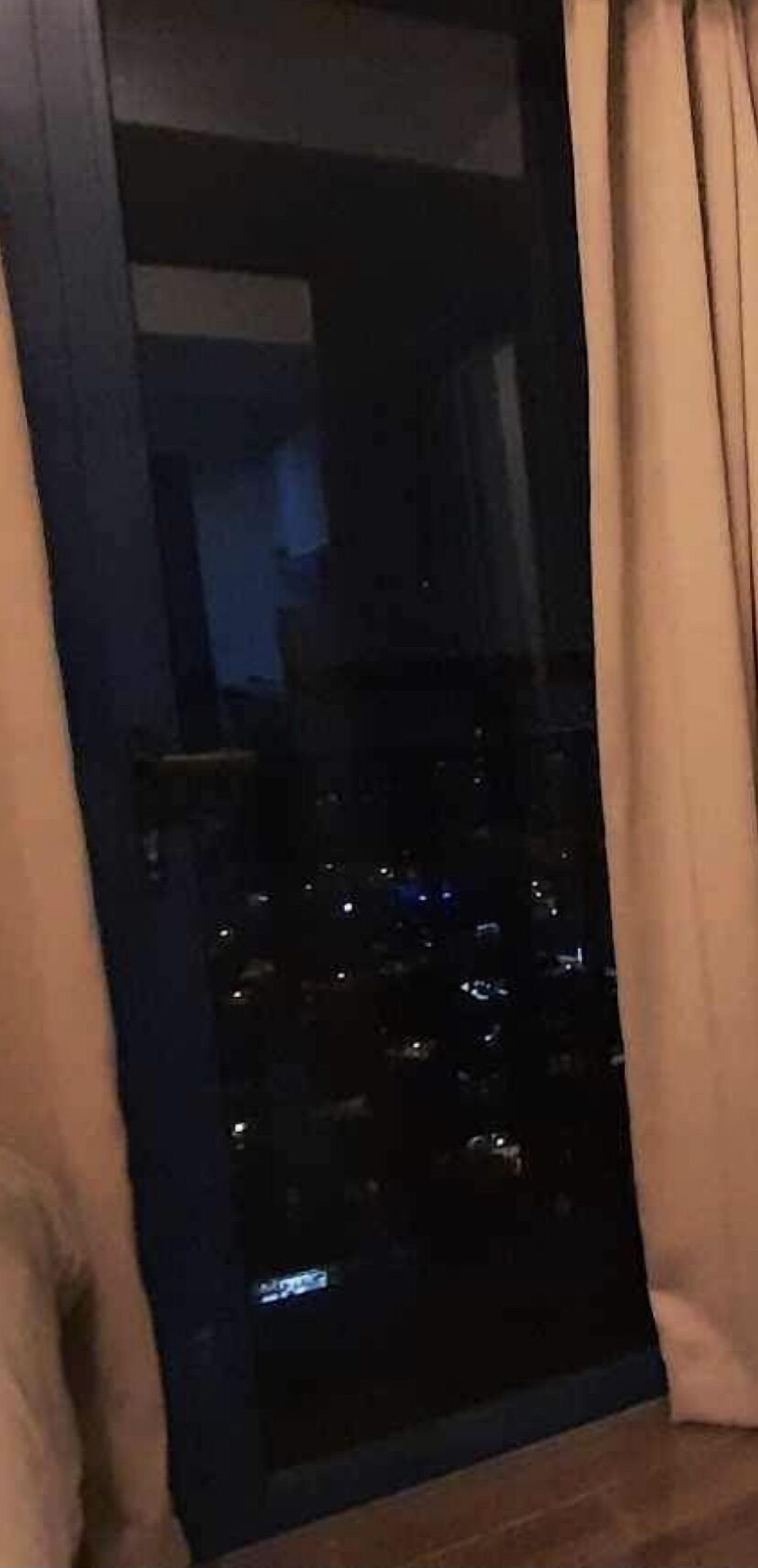 Een deur met een codeerapparaat, gordijnen en een spiegelbeeld van licht in het glas.