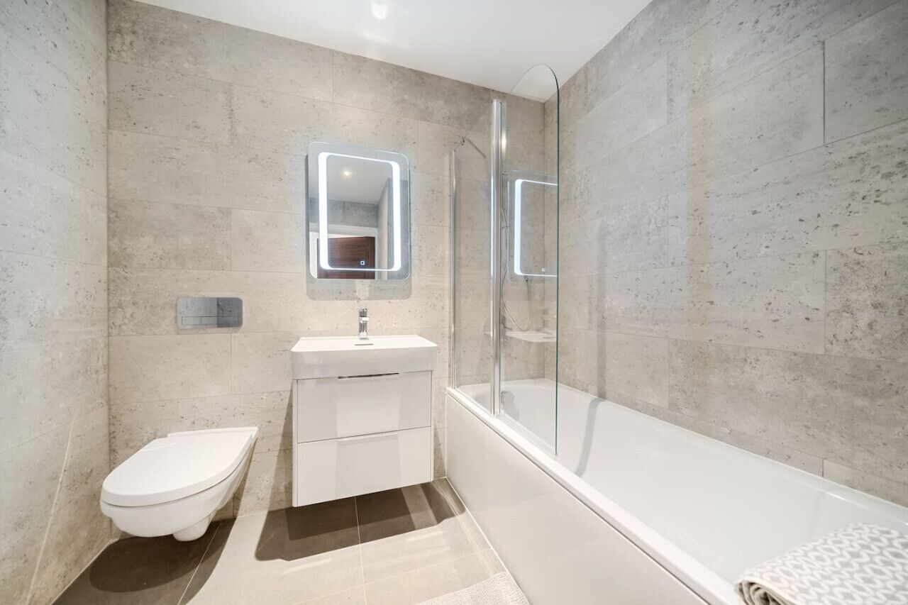 A modern bathroom with a toilet, sink, and bathtub.