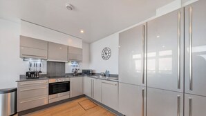 A modern kitchen with stainless steel appliances, a microwave, and a clock on the wall.