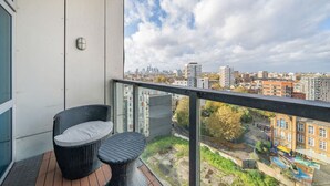 A balcony with wicker furniture, a city view, and a building with a clock.
