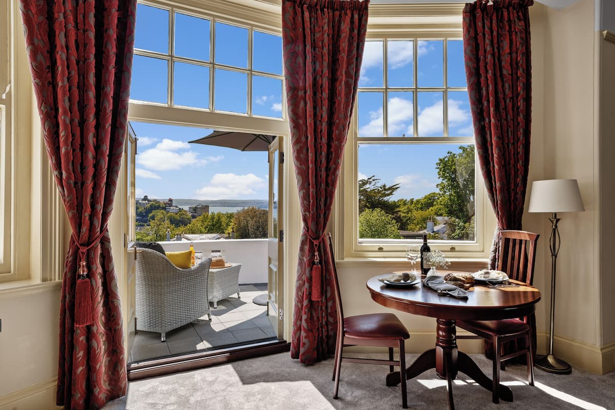 Une pièce comprenant une table à manger, des chaises, une lampe et une fenêtre donnant sur un paysage.