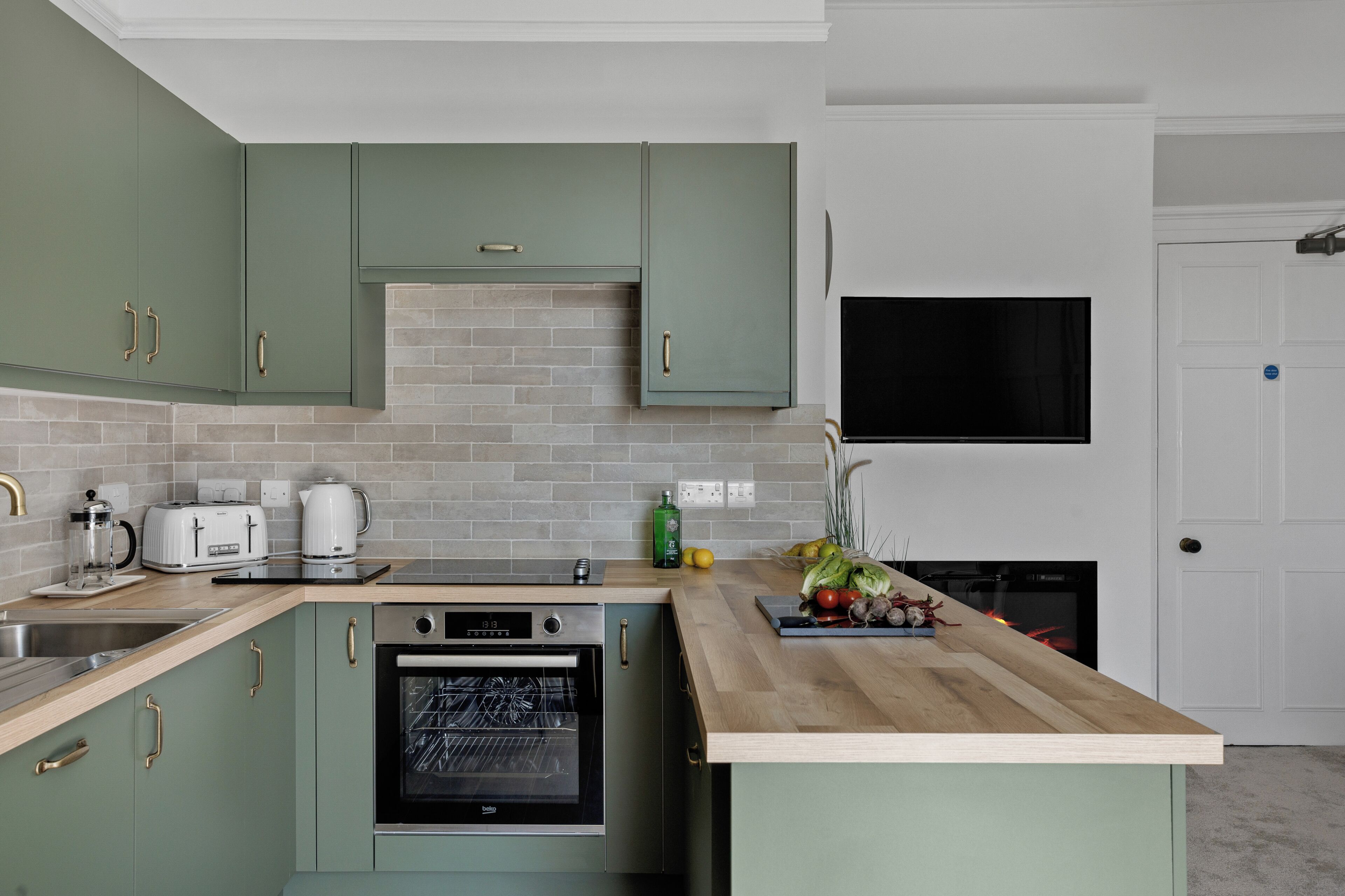 A kitchen with a built-in oven, a sink, and a countertop with a dish rack.
