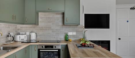A kitchen with a built-in oven, a sink, and a countertop with a dish rack.