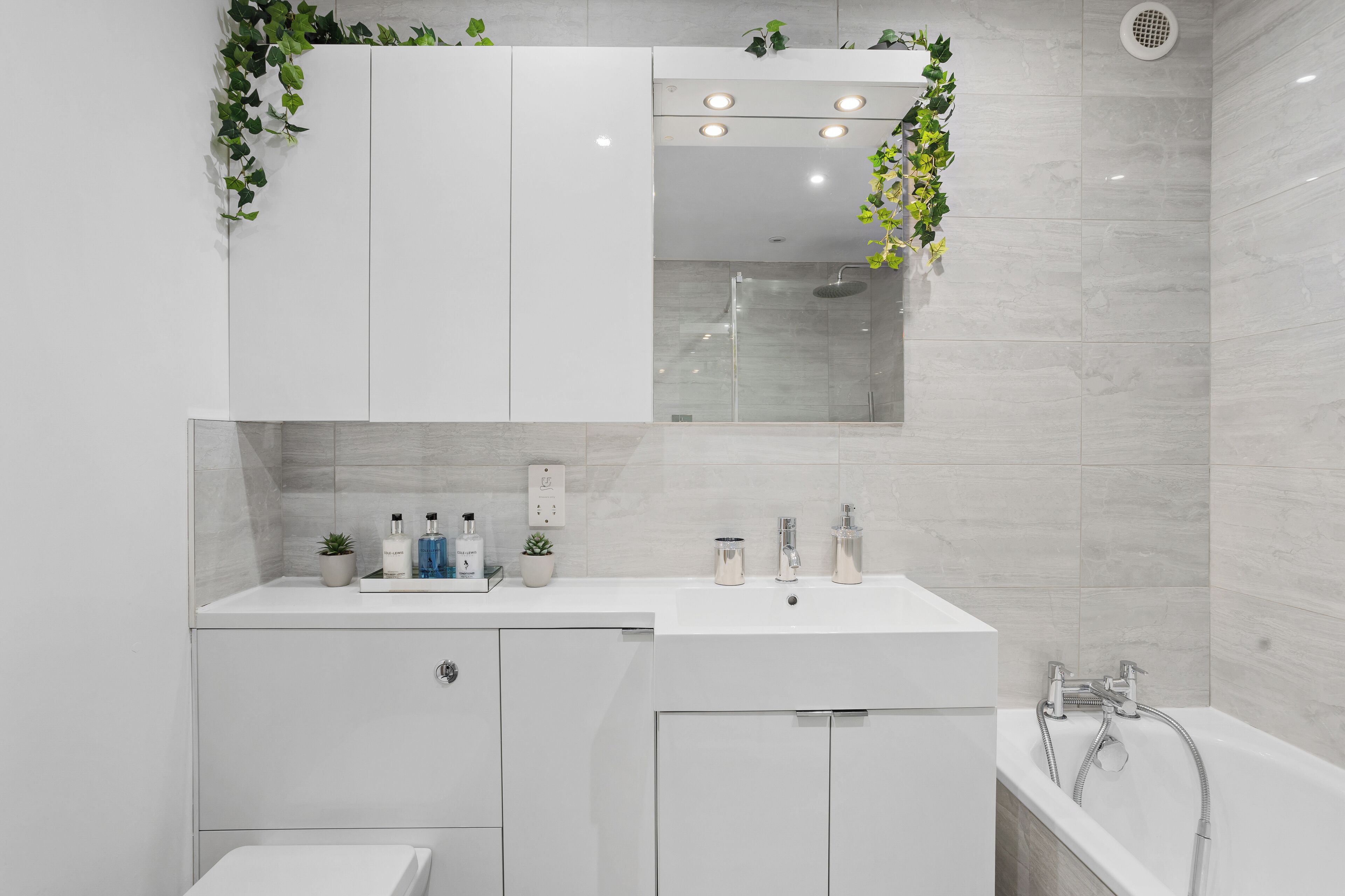 Une salle de bain moderne avec un meuble-lavabo blanc, un grand miroir et un espace douche.