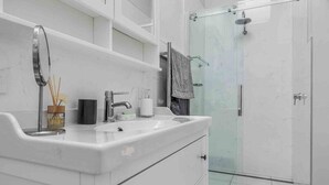 A modern bathroom with a white vanity, a glass shower enclosure, and a towel rack.