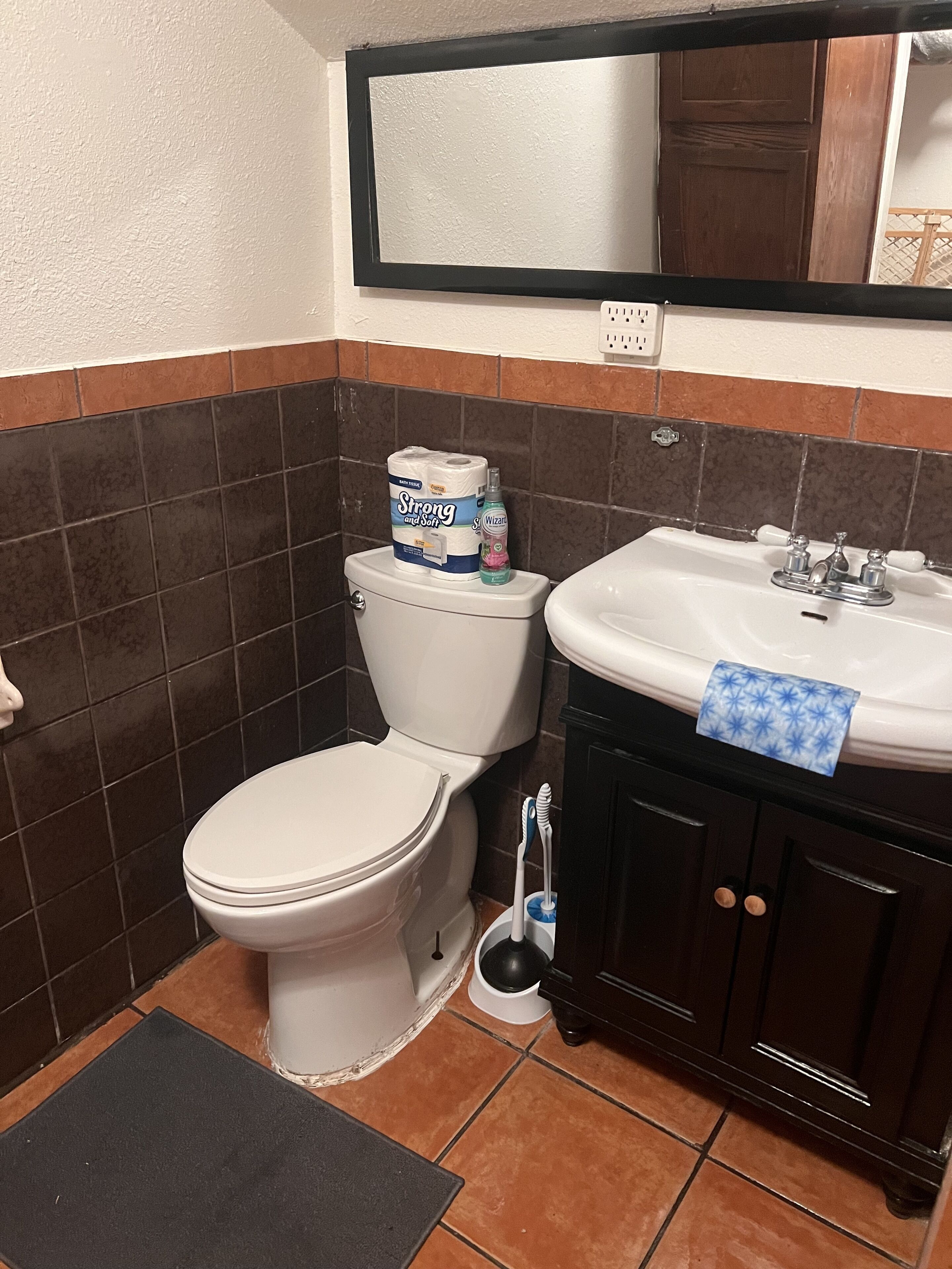A bathroom with a toilet, sink, and mirror.