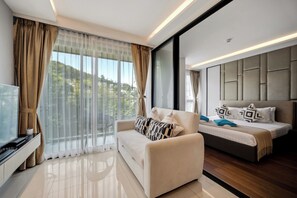 A modern hotel room with a sofa, a bed, and a TV. - The Panora apartments by NLA (Choeng Thale)