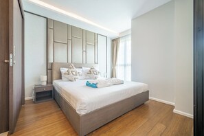 A modern bedroom with a large bed, a nightstand, and a window with curtains. - The Panora apartments by NLA (Choeng Thale)