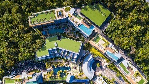 An aerial view of a resort with multiple buildings, a central pool, and surrounding greenery. - The Panora apartments by NLA (Choeng Thale)