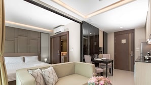 A modern hotel room with a bed, a sofa, a dining area, and a kitchenette. - The Panora apartments by NLA (Choeng Thale)