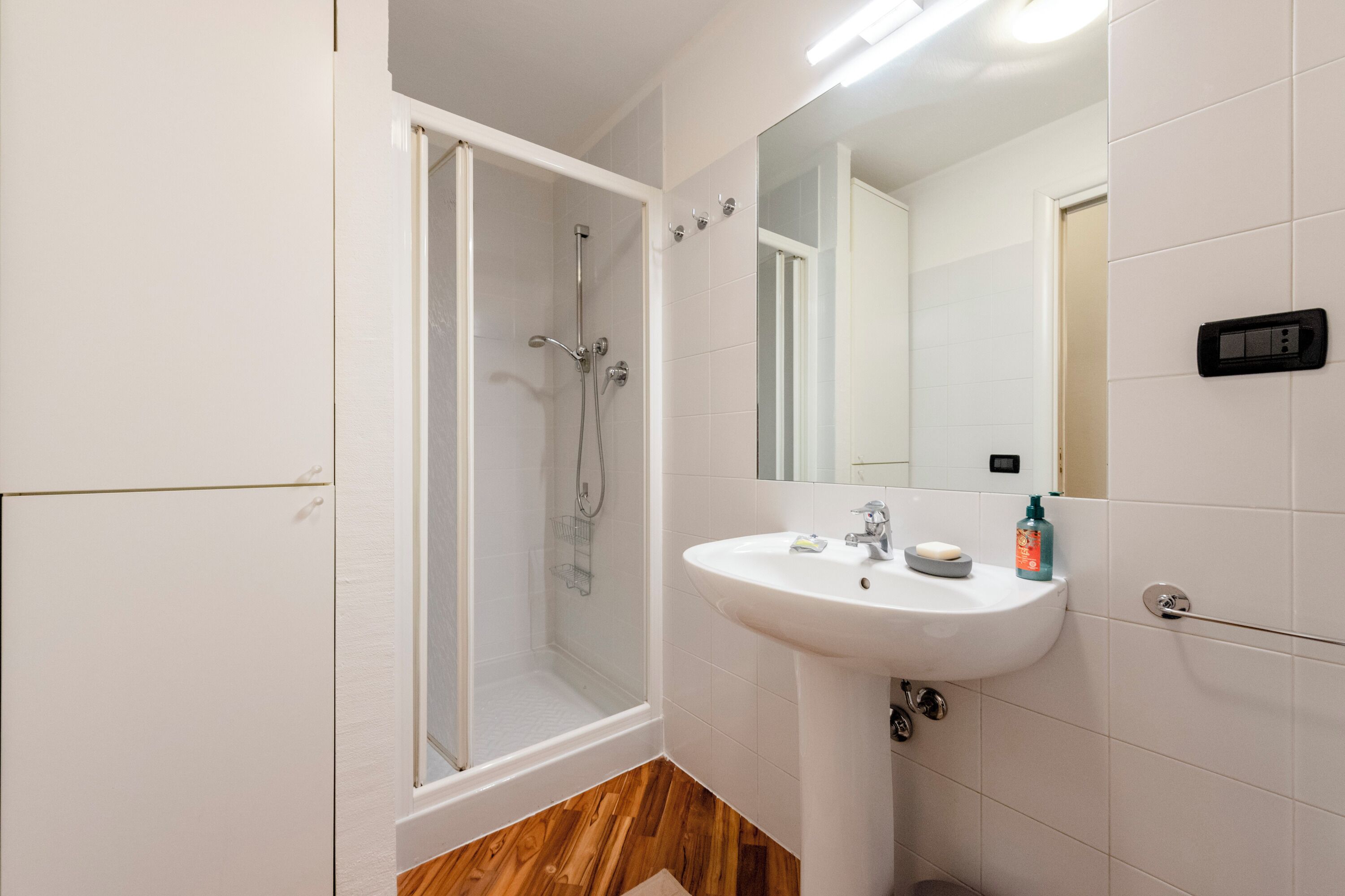 A modern bathroom with a glass-enclosed shower, a white sink, and a mirror.