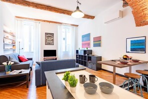 A modern living room with a sofa, coffee table, and a dining area with a table and chairs. - Charming Apartment Next To Genoa's Aquarium (Genoa)