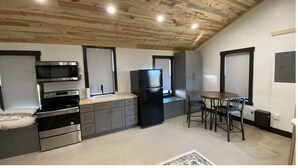 Une cuisine compacte équipée d’un four à micro-ondes, d’un four, d’un réfrigérateur et d’une table à manger avec des chaises.