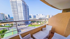 Ein Balkon mit Korbmöbeln und Blick auf eine Stadtlandschaft.