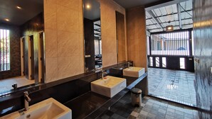 Un bagno moderno con tre lavandini, uno specchio grande e un cestino.