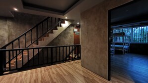 Un interno moderno con una scala in legno, una parete in cemento e un letto a castello sullo sfondo.
