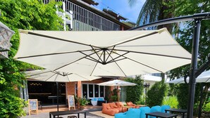 Patio esterno con tavoli, sedie e un'area con divani, ombrelloni per l'ombra.