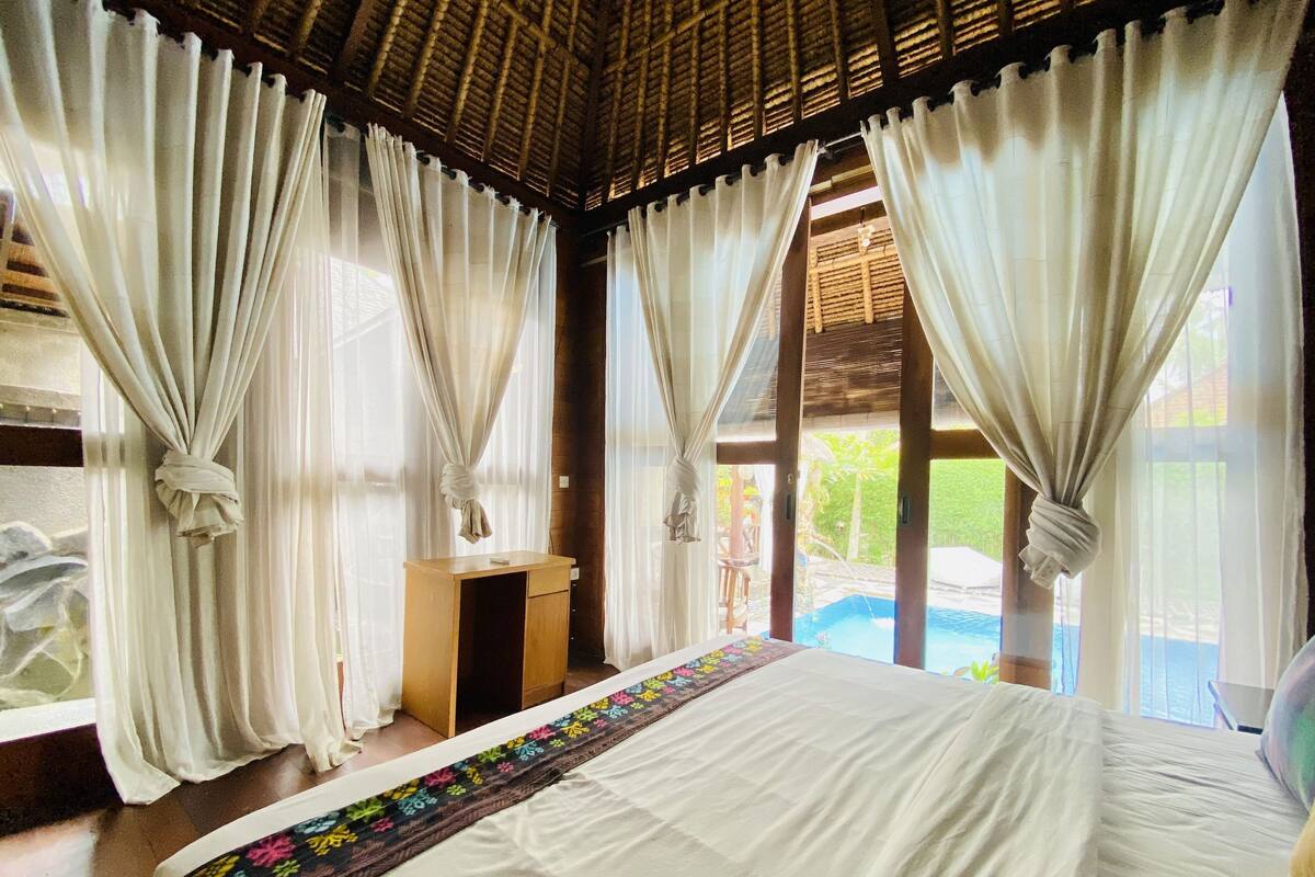 Un dormitorio con cama, escritorio y vista a una piscina.
