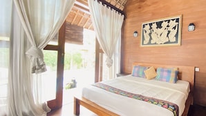 Un dormitorio con una cama de madera, cortinas blancas y una obra enmarcada en la pared.