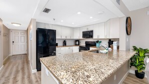 A modern kitchen with white cabinets, granite countertops, and stainless steel appliances.
