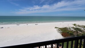 A beach with a clear sky, a sandy shore, and a few people and boats.