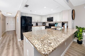 A modern kitchen with granite countertops, stainless steel appliances, and white cabinetry.