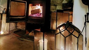 A cozy room with a stone fireplace, a television, and decorative lanterns. - Luxury Cosy Cottage In Magical Bibury (Bibury)