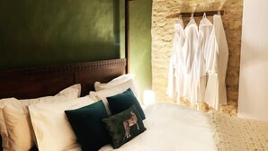 A neatly made bed with white and green pillows, a wooden headboard, and a stone wall. - Luxury Cosy Cottage In Magical Bibury (Bibury)