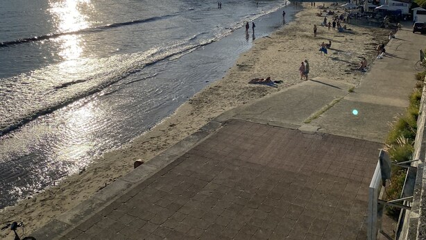 A beach with a paved walkway, a bicycle, and buildings in the background. - Appartement Terrasse (Royan)