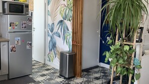 A kitchen with a microwave, refrigerator, and a potted plant. - Appartement Terrasse (Royan)