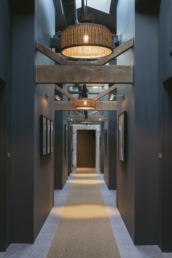 Een moderne hal met een centrale doorgang, ingelijste kunstwerken en een hanglamp.