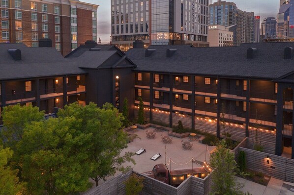 A multi-story building with a courtyard featuring outdoor seating and string lights.