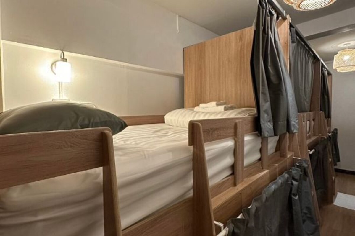 A bunk bed with wooden headboards, a bedside lamp, and a hanging light fixture.