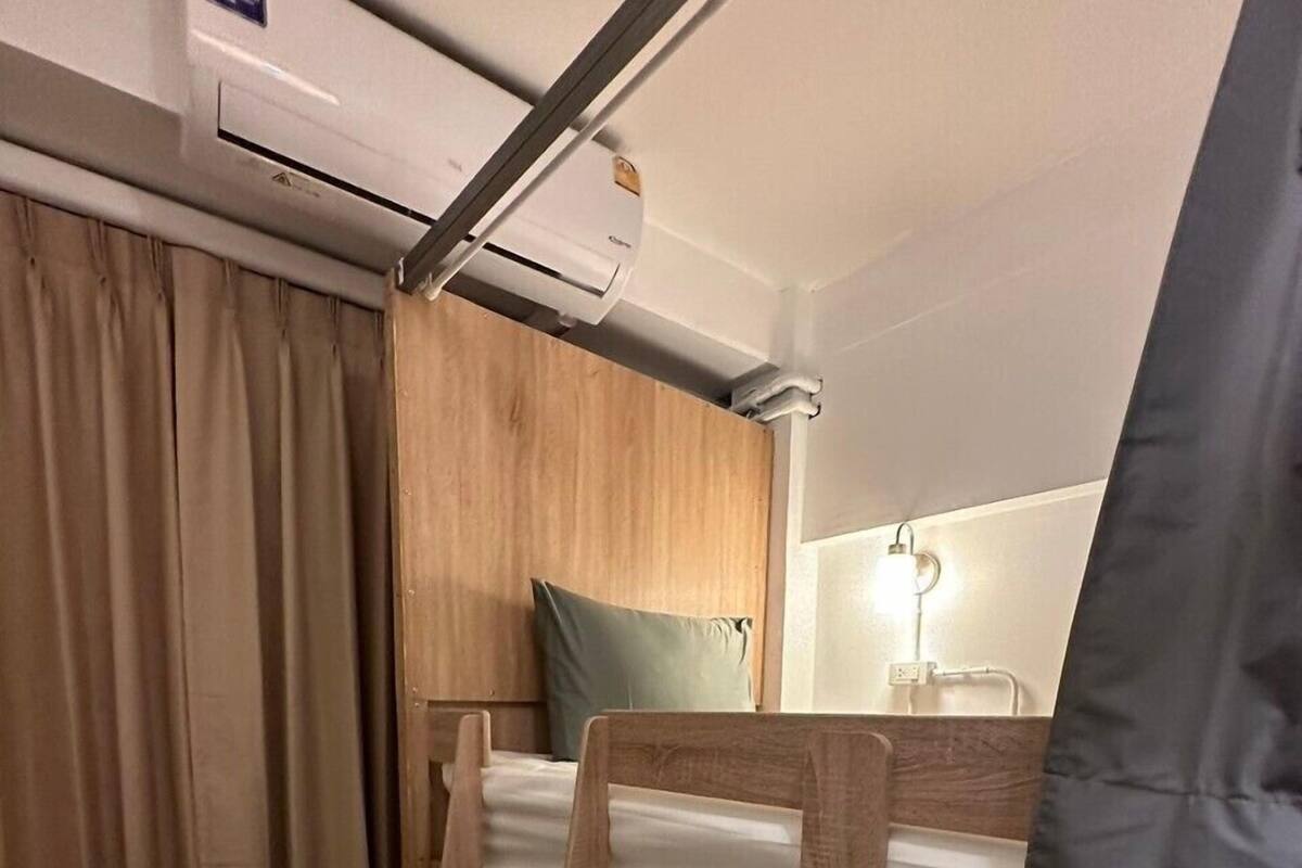 A bunk bed room with a wooden headboard, a small ladder, a curtain, and an air conditioning unit.