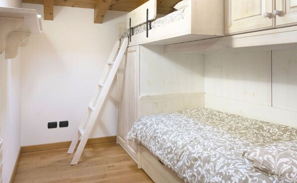 A small, compact room with a bunk bed, a wooden ladder, and a white wall. - La Mansarda in Ponte di Legno (Ponte di Legno)