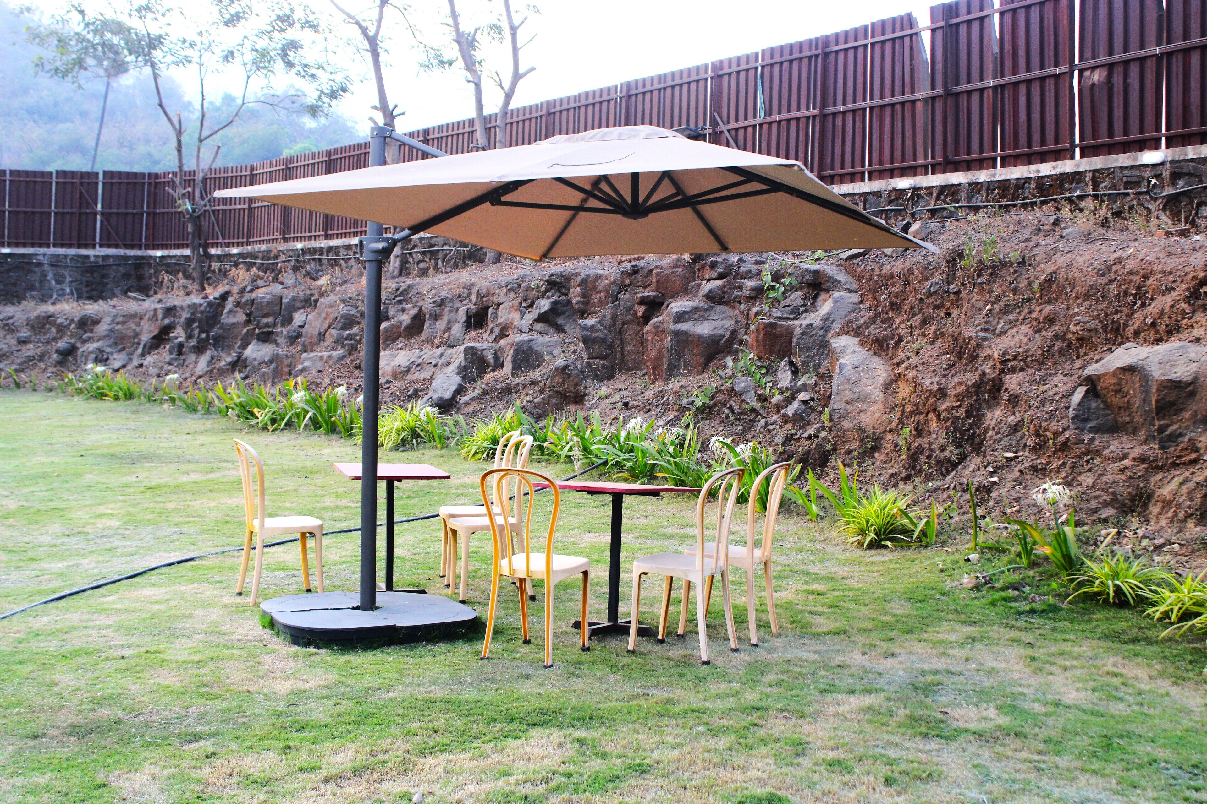 An outdoor patio with a table and chairs, a large umbrella, and a stone wall in the background.