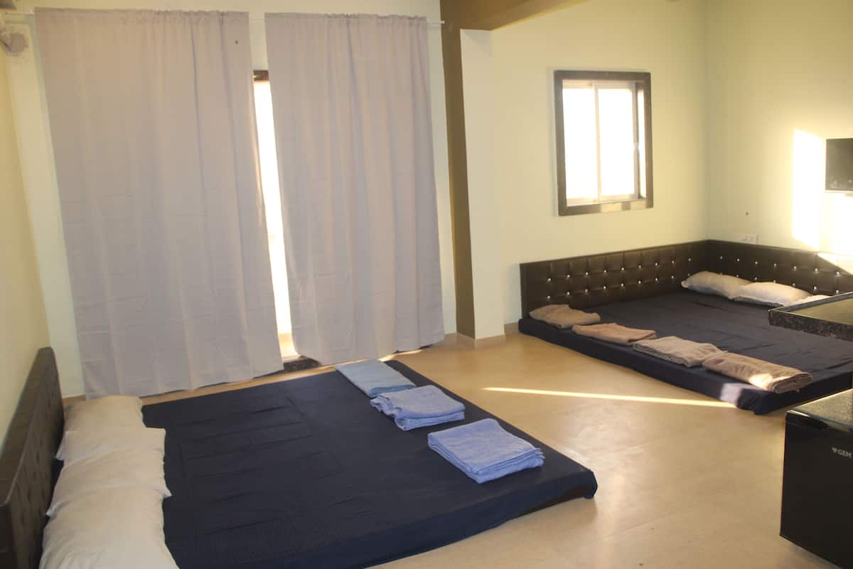 A room with two beds, a window, and a television.