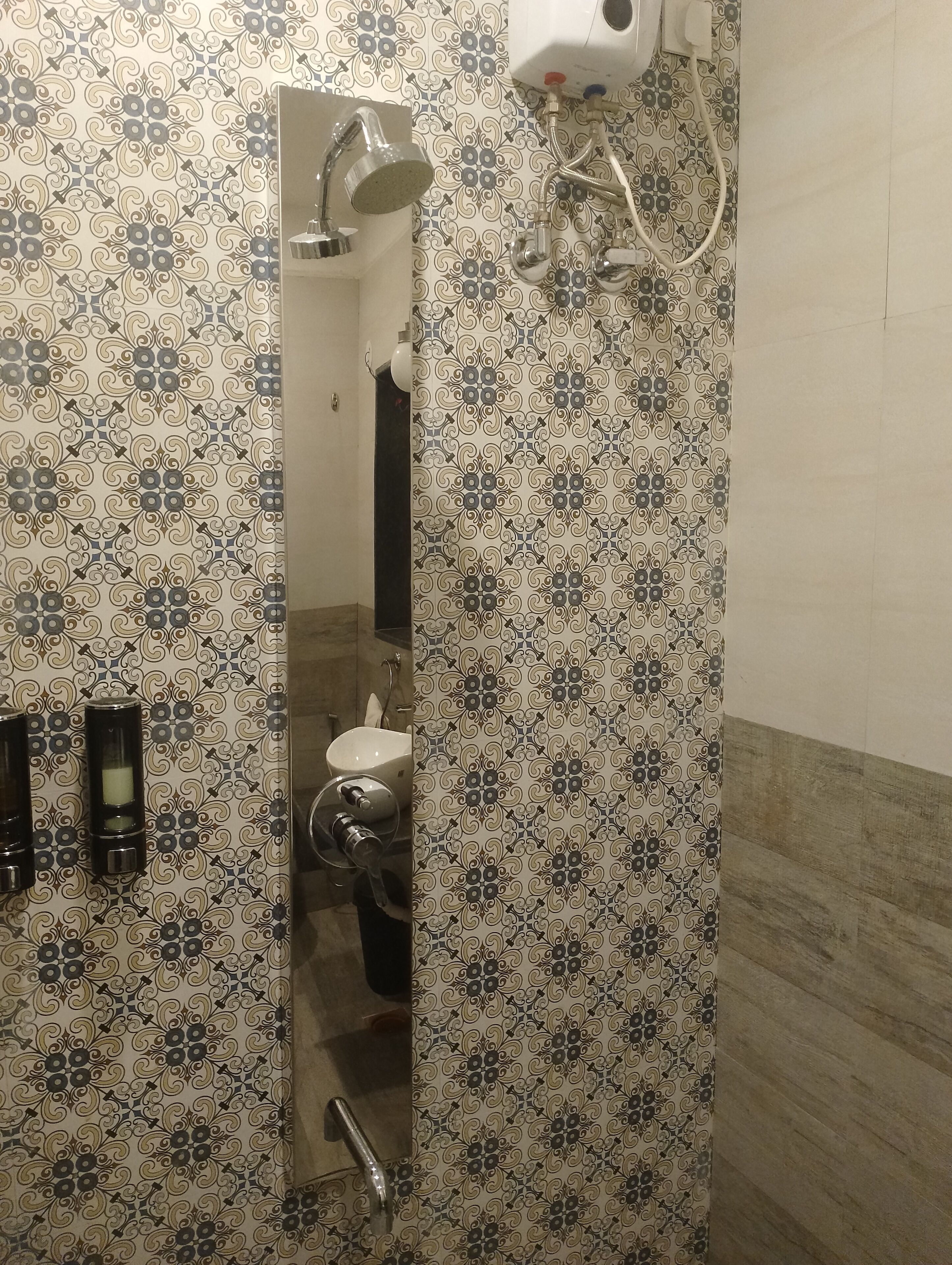 A bathroom with patterned tiles, a shower, a toilet, and a sink.