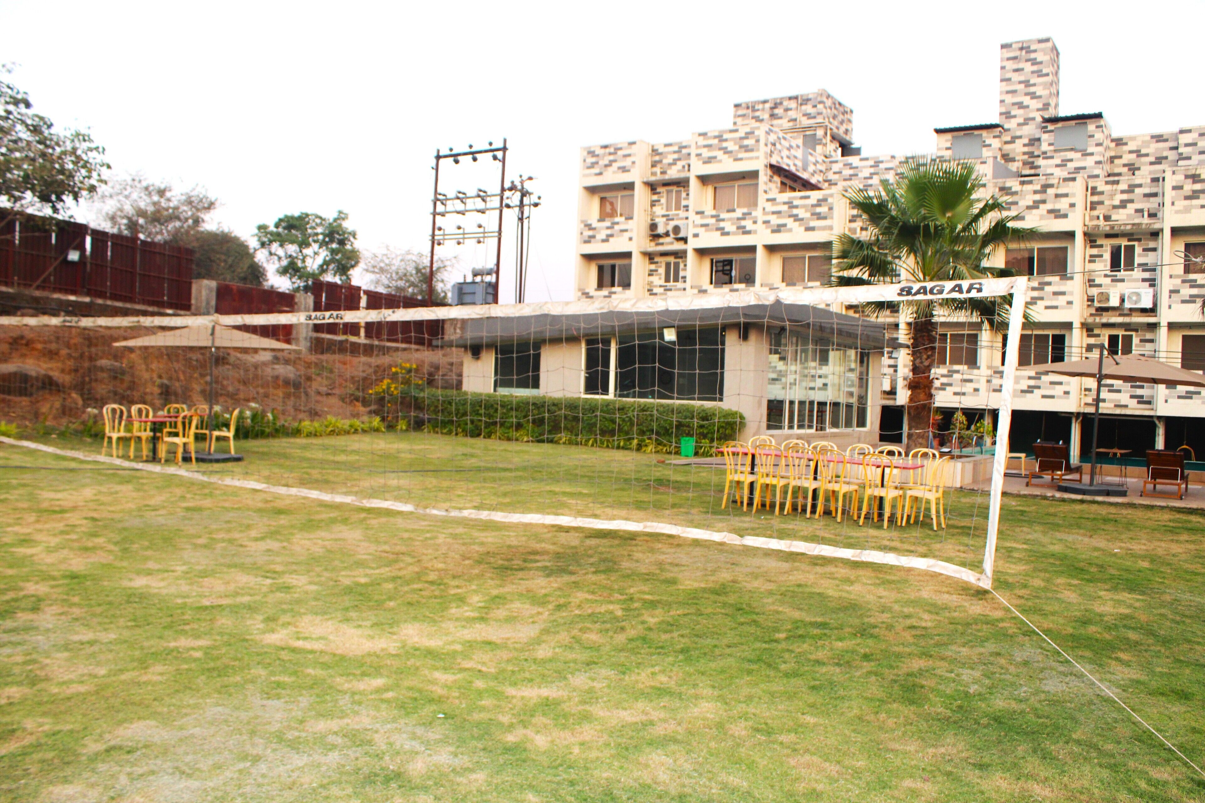 A sports field with a volleyball net, chairs, and a building labeled "SAGAR" in the background.