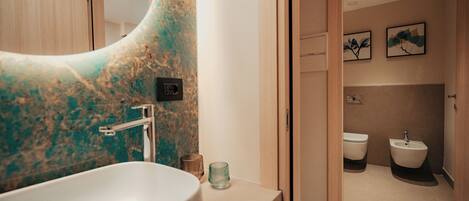 A modern bathroom with a large sink, a bidet, and a toilet.
