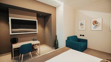 Quarto de hotel moderno com uma cama grande, uma mesa com cadeira, TV na parede e duas obras de arte emolduradas.