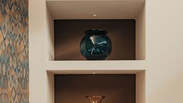 A wall-mounted shelf with three glass vases of different shapes and sizes.