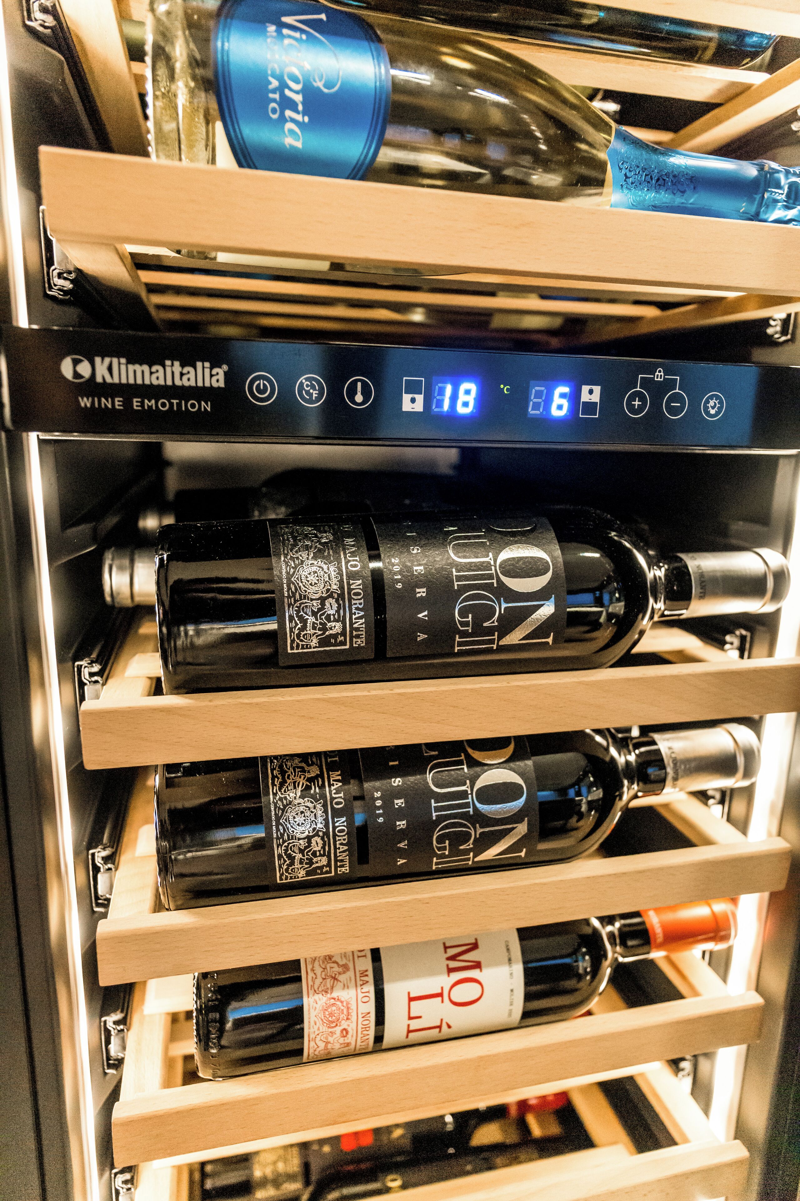 Frigorifero per vino con diverse bottiglie e display digitale della temperatura.